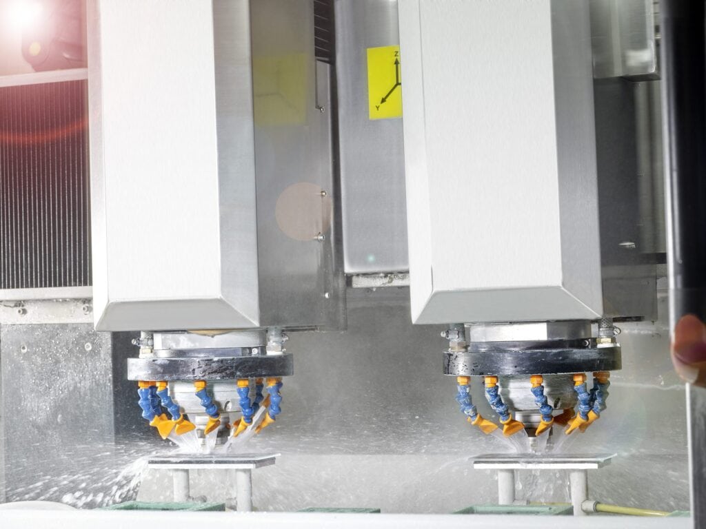 Schleifscheibe bearbeitet die Kante einer blauen Glasplatte auf der CNC bei MBM Techglas