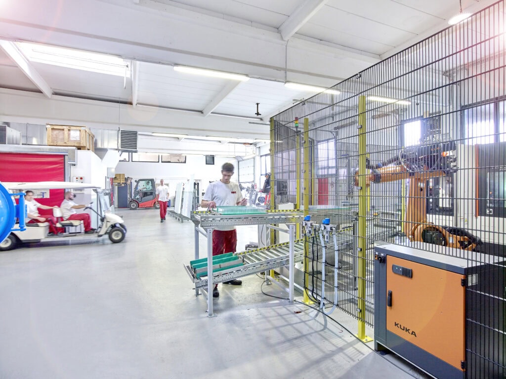 Mitarbeiter am Rollenförderer vor der Roboterzelle in der Fertigung von MBM Techglas