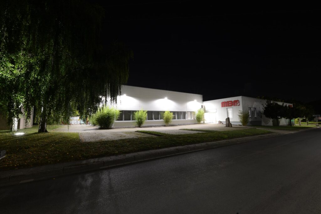 Firmengebäude von MBM Techglas in Unna bei Nacht, beleuchtete Fassade mit MBM-Logo